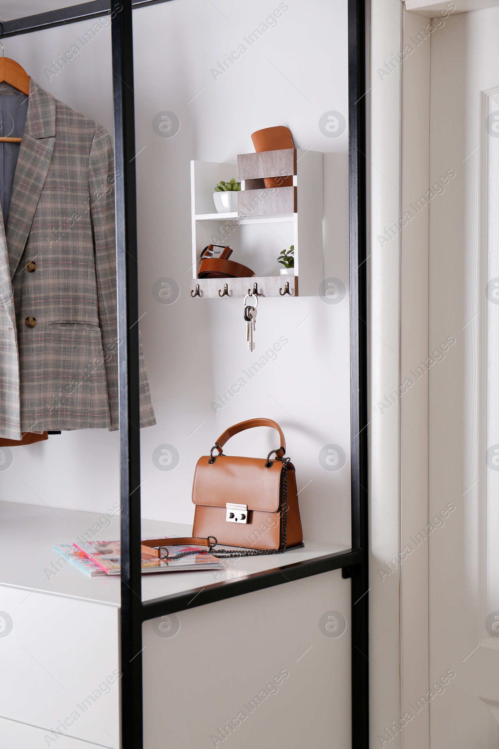 Photo of Hallway interior with stylish furniture, accessories and wooden hanger for keys on white wall