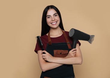 Photo of Portrait of happy hairdresser with hairdryer and vent brush on beige background