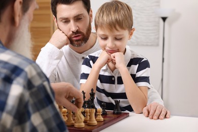 Family playing chess together at table in room