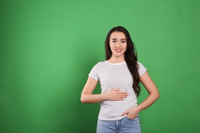 Photo of Happy healthy woman touching her belly on green background, space for text