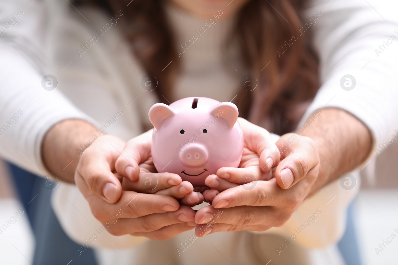 Photo of Couple holding pink piggy bank, closeup view