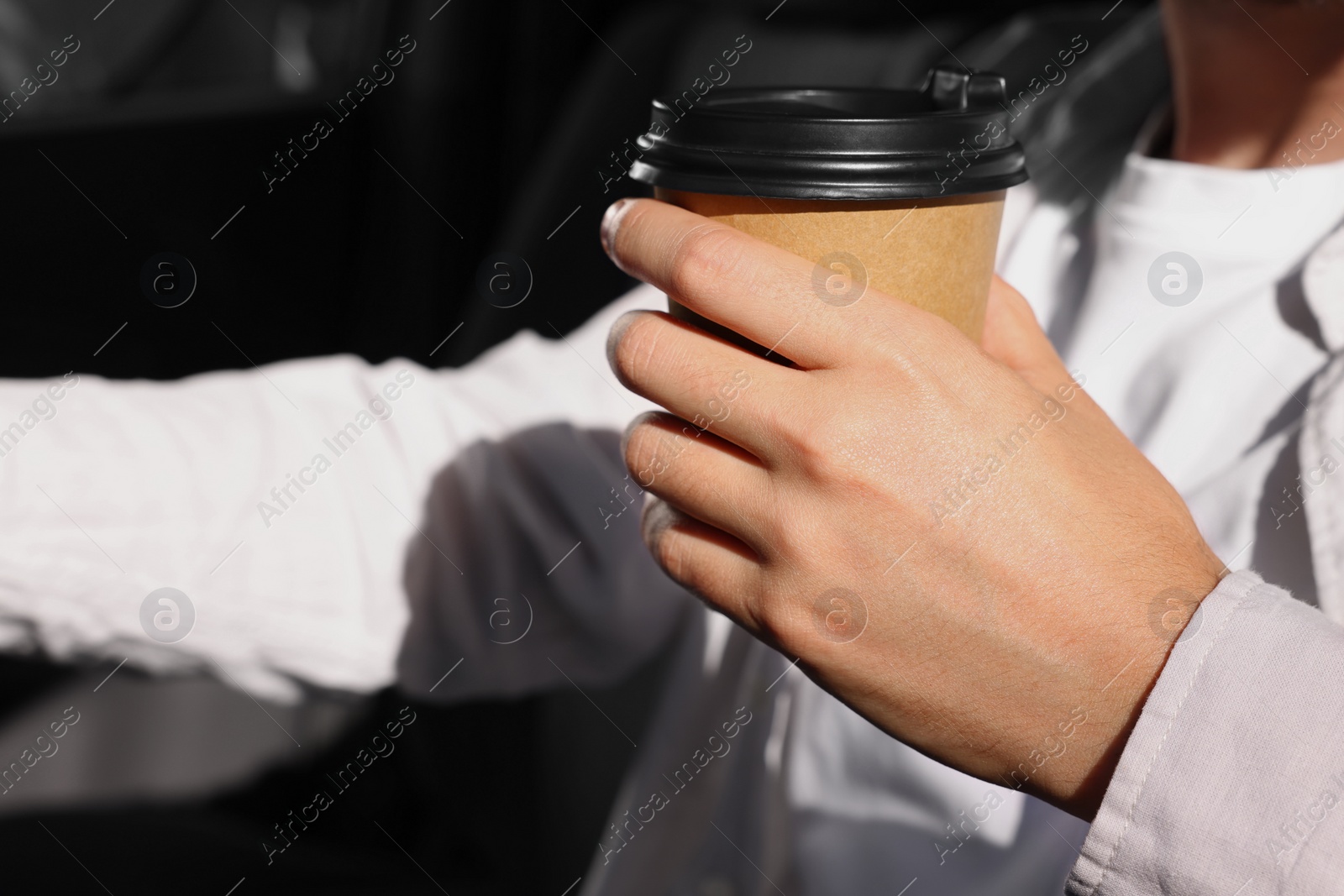 Photo of Coffee to go. Man with paper cup of drink in car, closeup