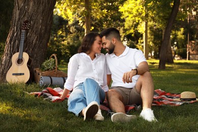Photo of Lovely couple spending time together on picnic plaid in park