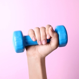 Photo of Woman holding vinyl dumbbell on color background, closeup