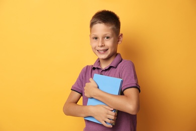 Photo of Portrait of cute little boy with books on yellow background. Reading concept