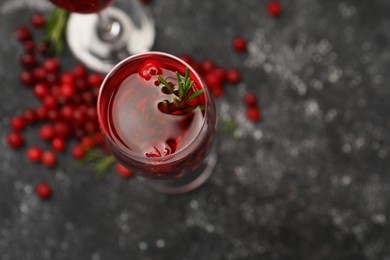 Photo of Tasty cranberry cocktail with rosemary in glass on gray table, above view. Space for text