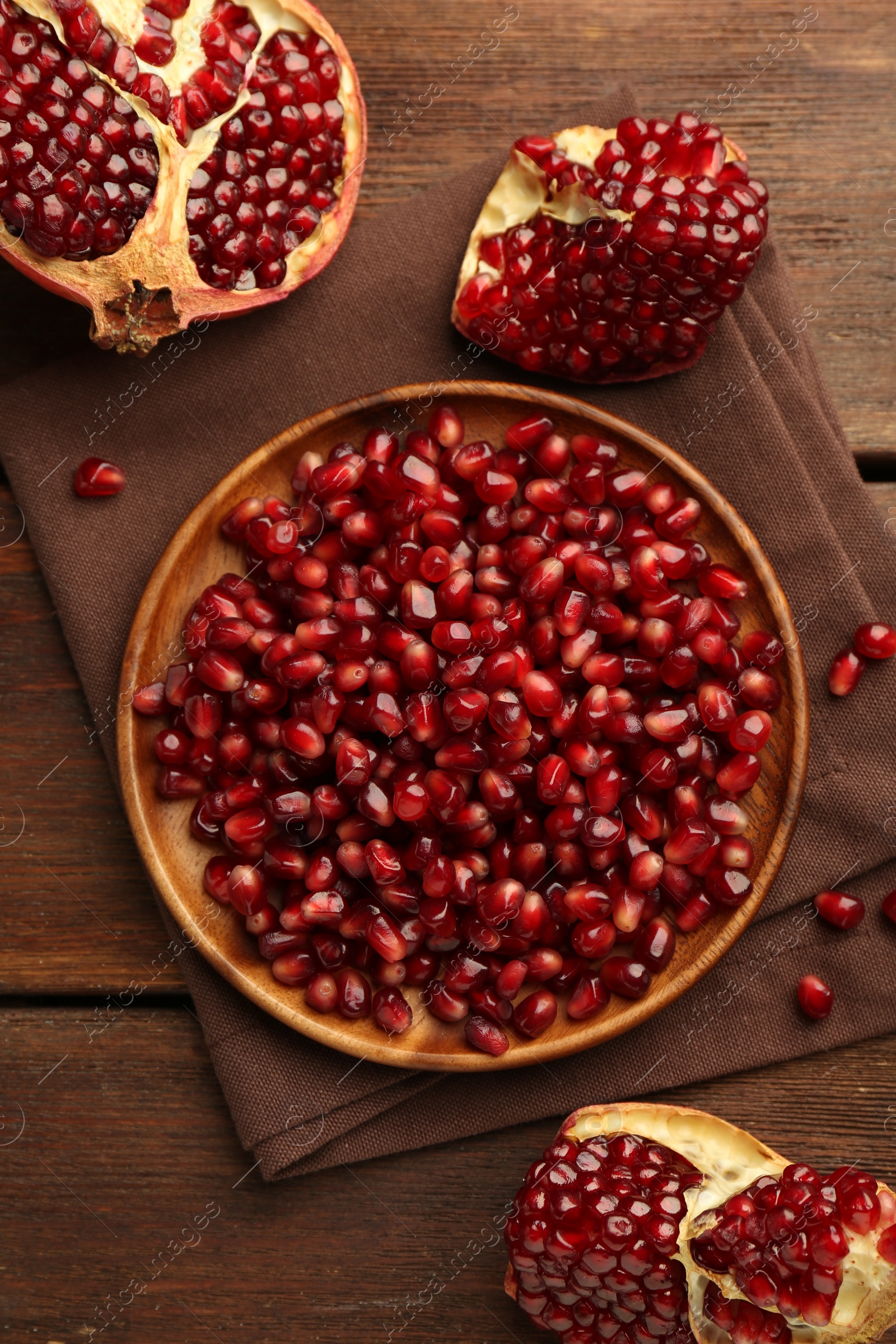 Photo of Ripe juicy pomegranates and grains on wooden table, flat lay