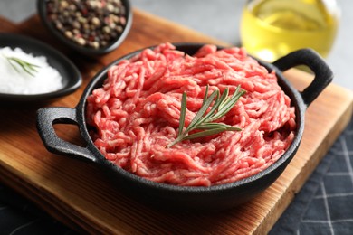 Raw ground meat in bowl and spices on table, closeup