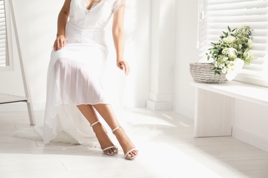Photo of Young bride wearing beautiful wedding dress in room, closeup