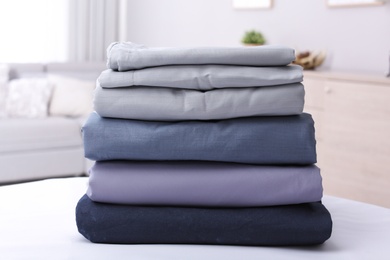 Photo of Stack of clean bed linens on table in room