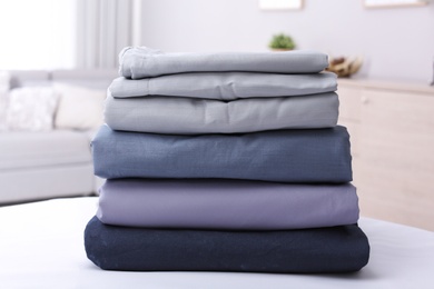 Stack of clean bed linens on table in room