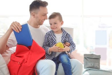 Young man helping his little child get ready for school at home