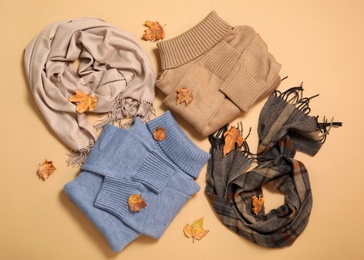 Photo of Flat lay composition with sweater and dry leaves on beige background. Autumn season