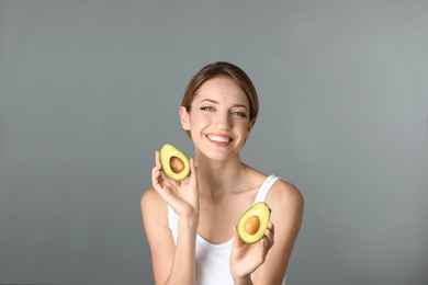 Portrait of young beautiful woman with ripe delicious avocado on color background