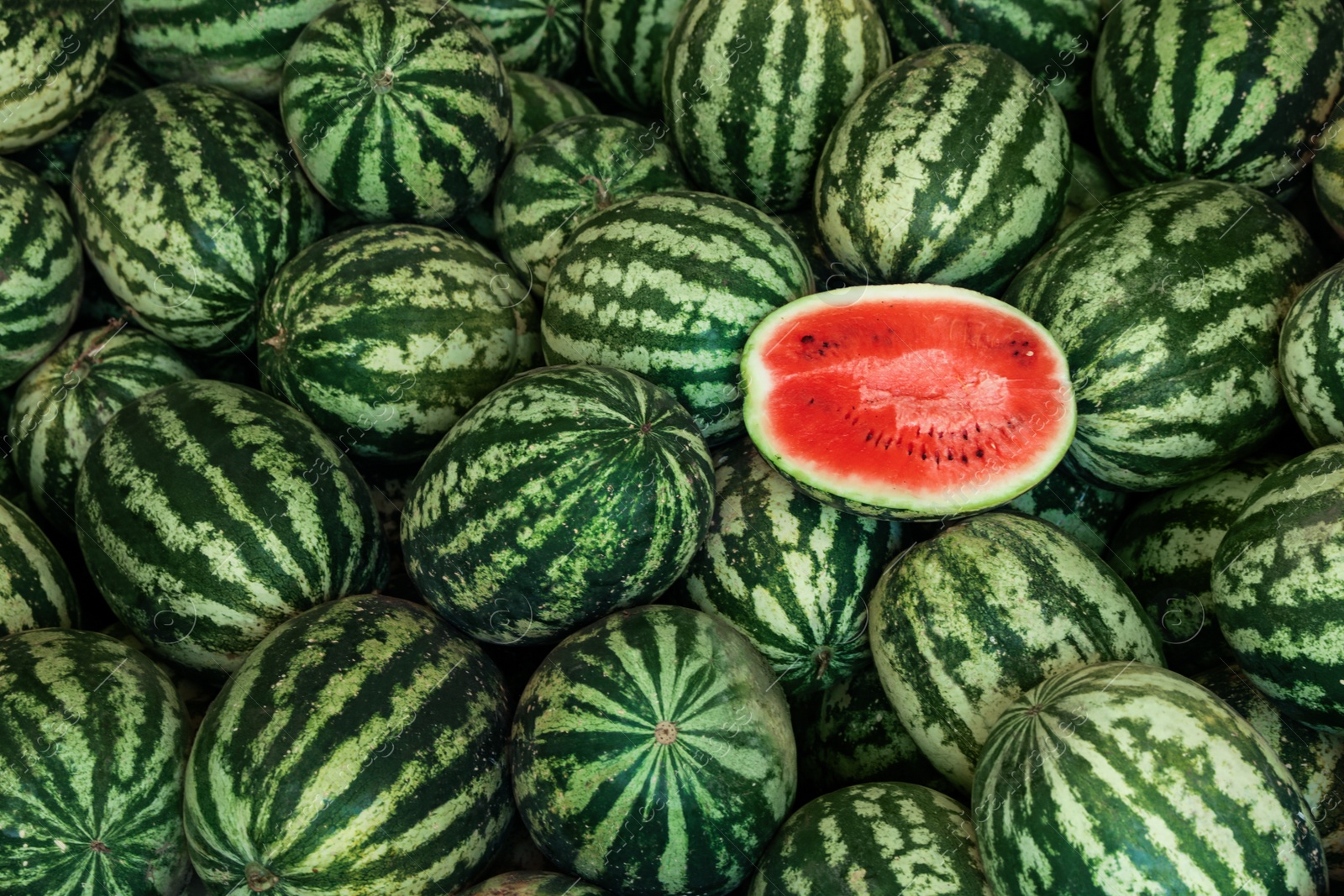 Photo of Delicious whole and cut watermelons as background, top view