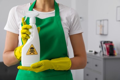 Photo of Woman showing toxic household chemical spray with warning sign, closeup