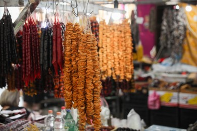 Bunches of different delicious churchkhelas and dried figs at market, space for text