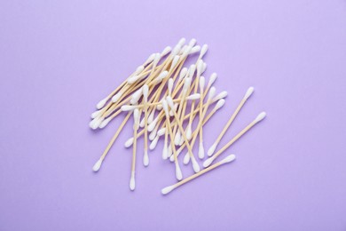 Photo of Wooden cotton buds on violet background, flat lay