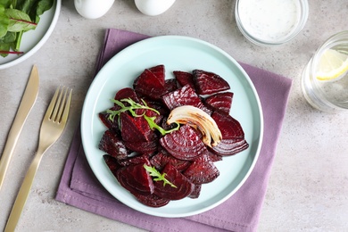 Photo of Roasted beetroot slices with onion and arugula served on light grey table, flat lay