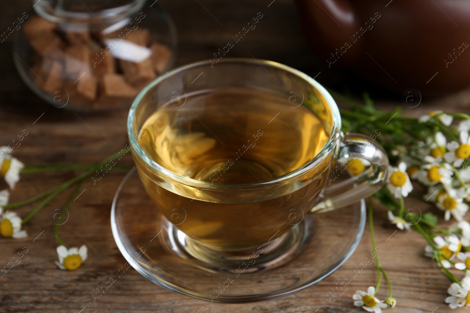 Photo of Delicious chamomile tea in glass cup on wooden table