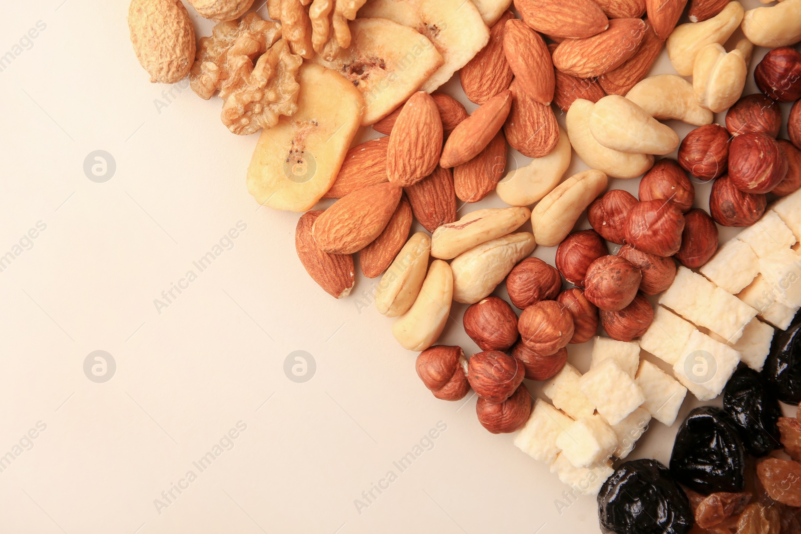 Photo of Different tasty nuts and dried fruits on beige background, flat lay. Space for text