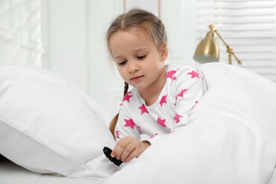 Photo of Sad little girl finding piece of coal under pillow in bed at home. Saint Nicholas day tradition