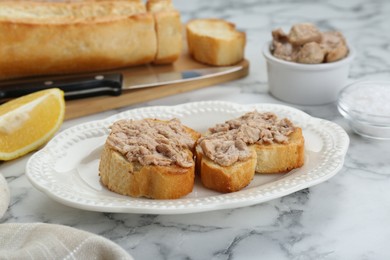 Photo of Tasty sandwiches with cod liver and lemon on white marble table