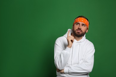 Photo of Fashionable young man in stylish outfit with bandana on green background, space for text