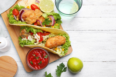 Photo of Delicious fish tacos served on white wooden table, flat lay