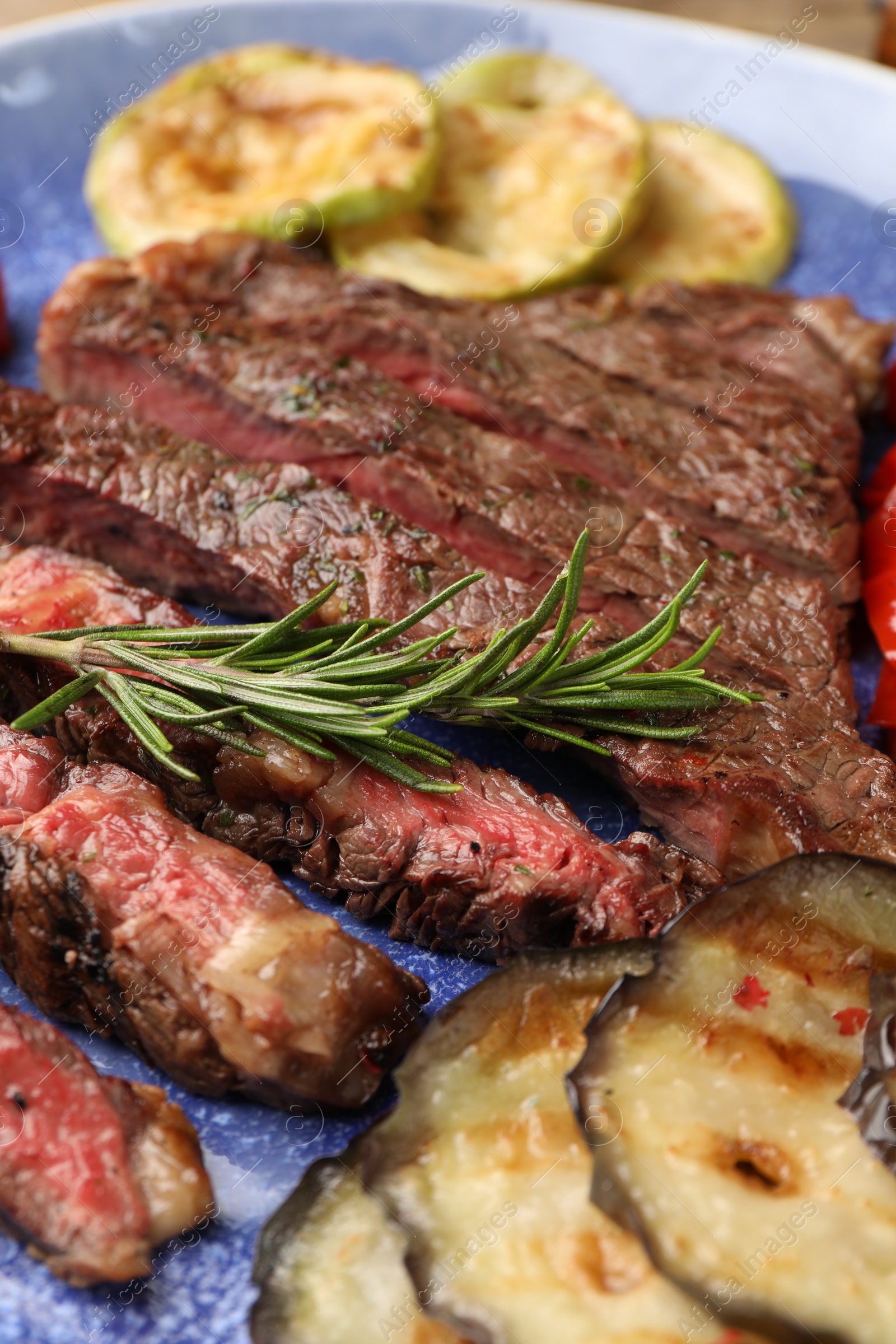 Photo of Delicious grilled beef with vegetables and rosemary on plate, closeup