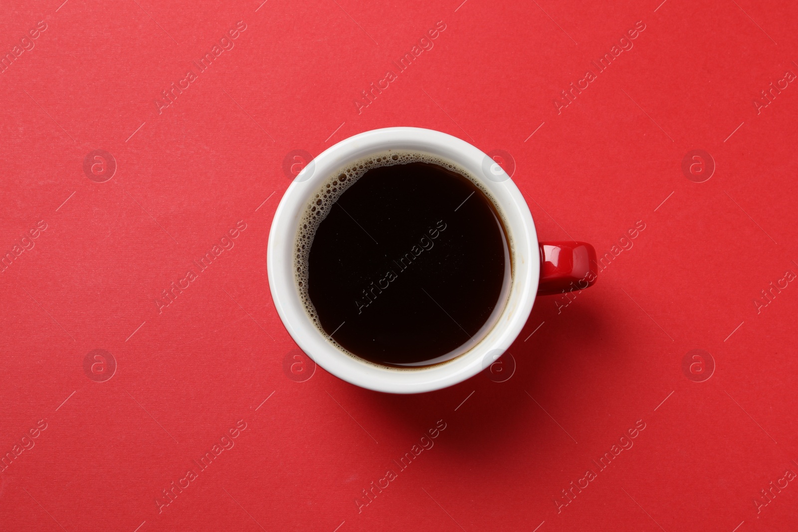 Photo of Aromatic coffee in cup on red background, top view