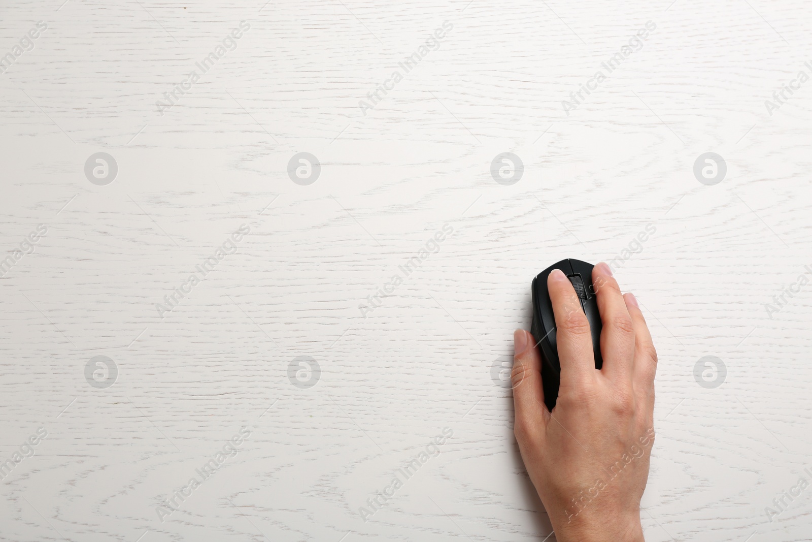 Photo of Woman using computer mouse on wooden table, top view. Space for text