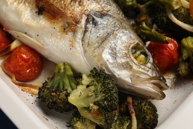 Delicious fish with vegetables in baking dish, closeup