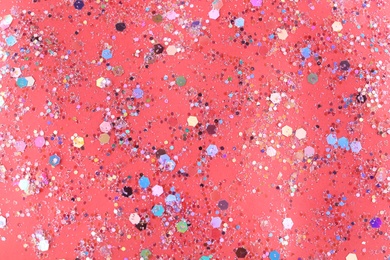 Photo of Shiny glitter on red background, top view