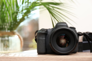 Professional camera on table against blurred background, space for text. Photographer's equipment