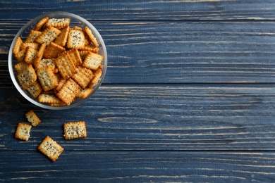 Photo of Delicious crispy crackers on blue wooden table, flat lay. Space for text