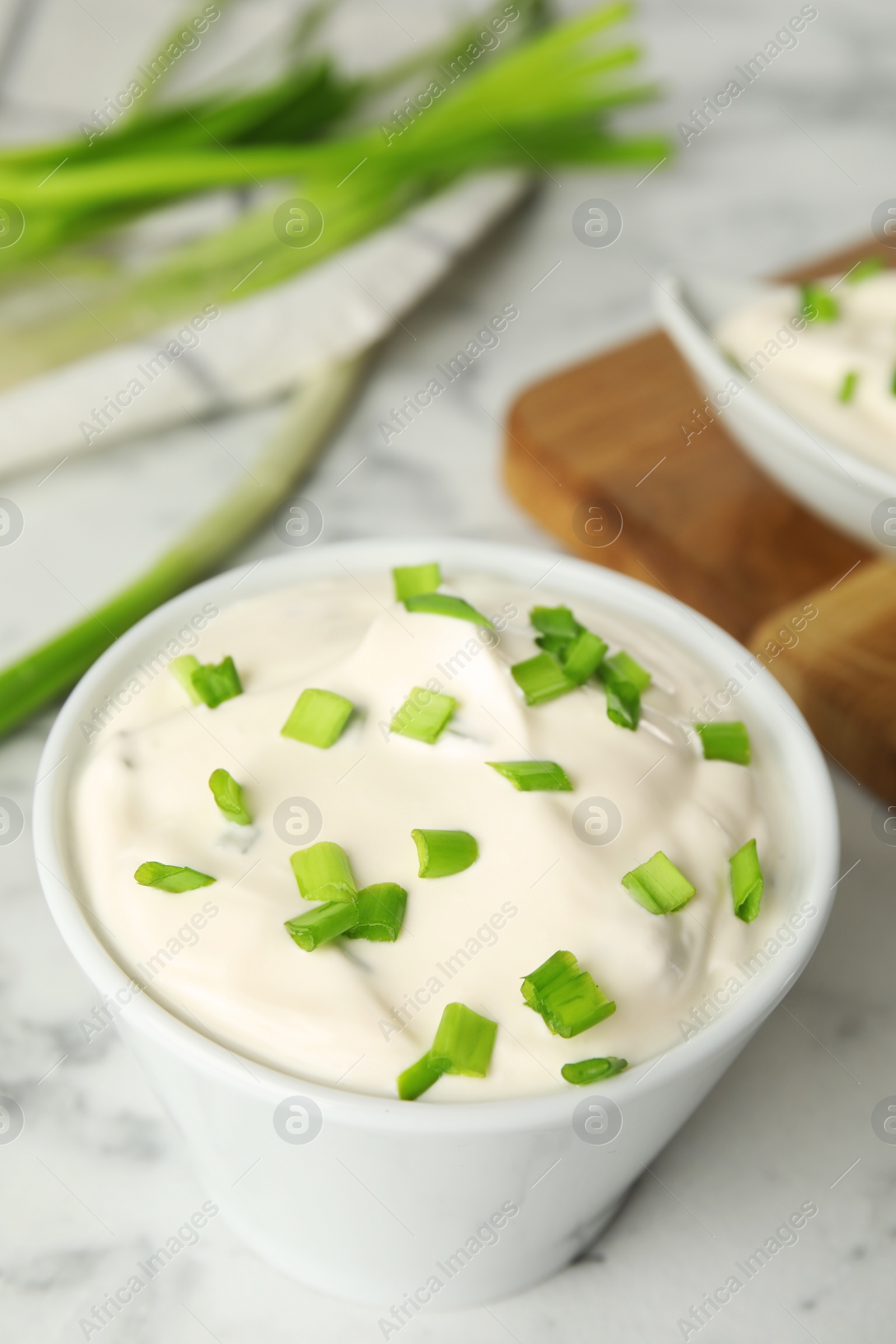 Photo of Fresh sour cream with onion on white marble table, closeup