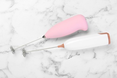 Photo of Pink milk frother wands on white marble table, top view