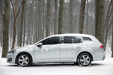 Photo of Car with winter tires on snowy road in forest, space for text