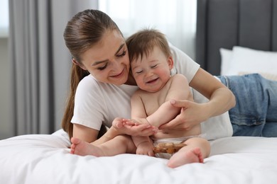 Happy mother with her baby on bed at home