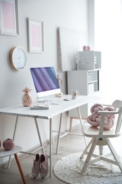 Photo of Contemporary workplace with computer on table near white wall. Interior design