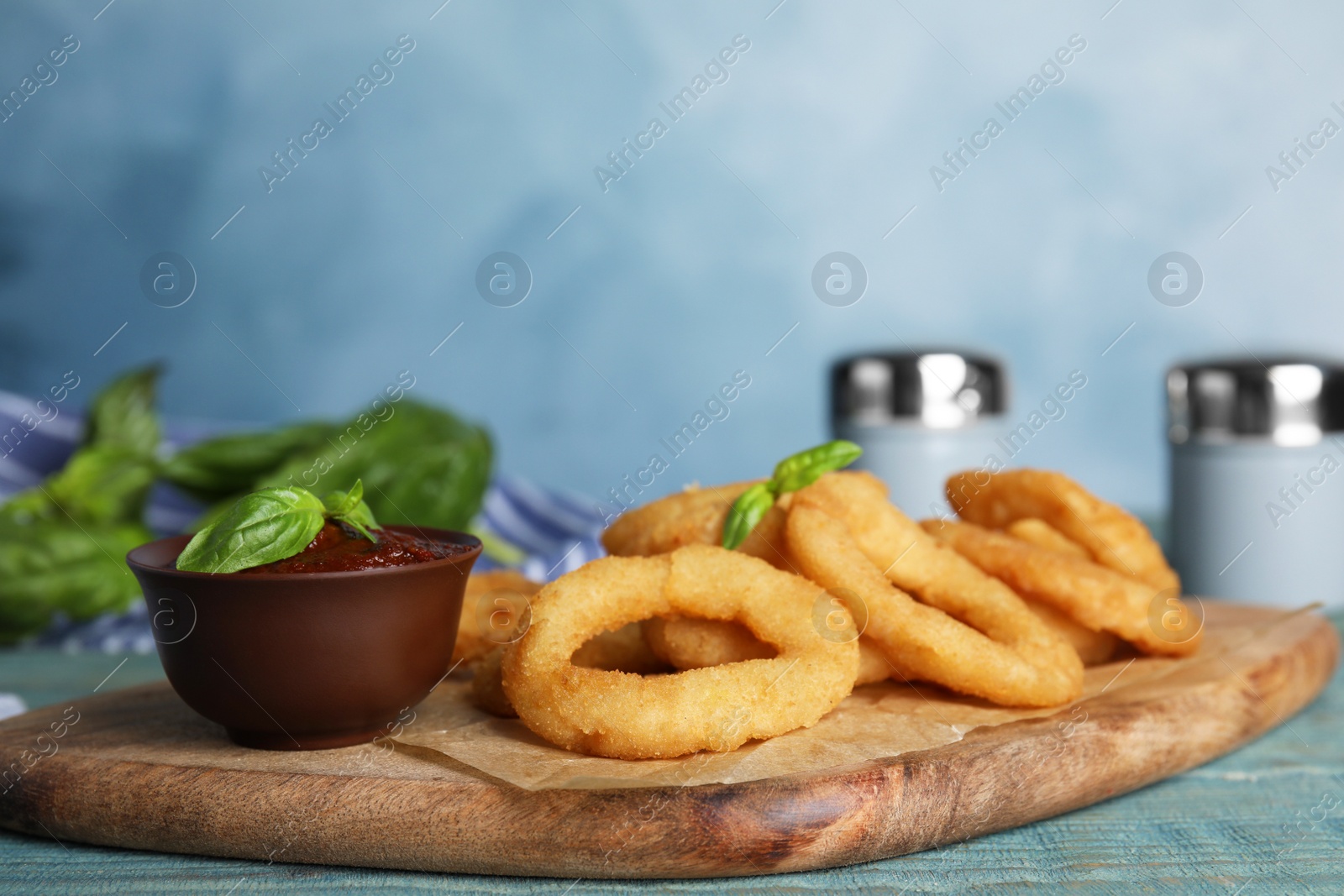 Photo of Fried onion rings served on blue wooden table