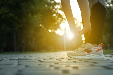 Woman stretching before morning run in park, closeup. Space for text