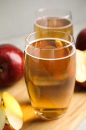 Photo of Delicious cider and ripe red apples on wooden board, closeup