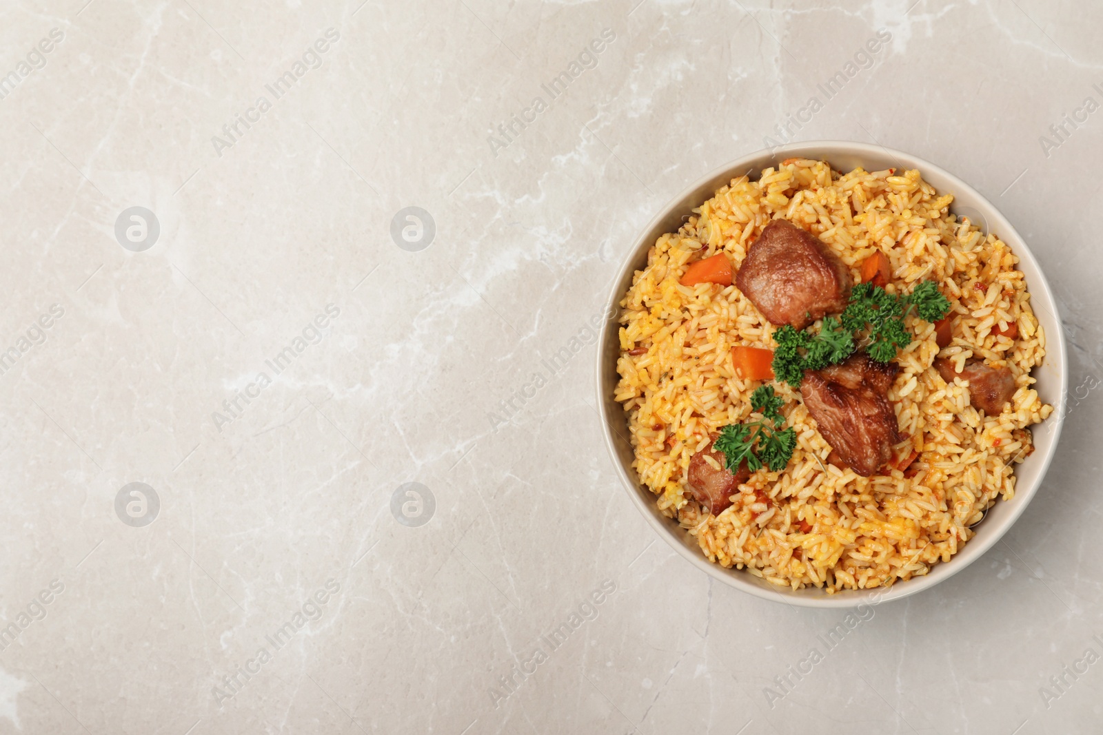 Photo of Bowl of delicious rice pilaf on light background, top view with space for text