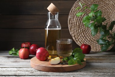 Delicious cider and apples with green leaves on wooden table
