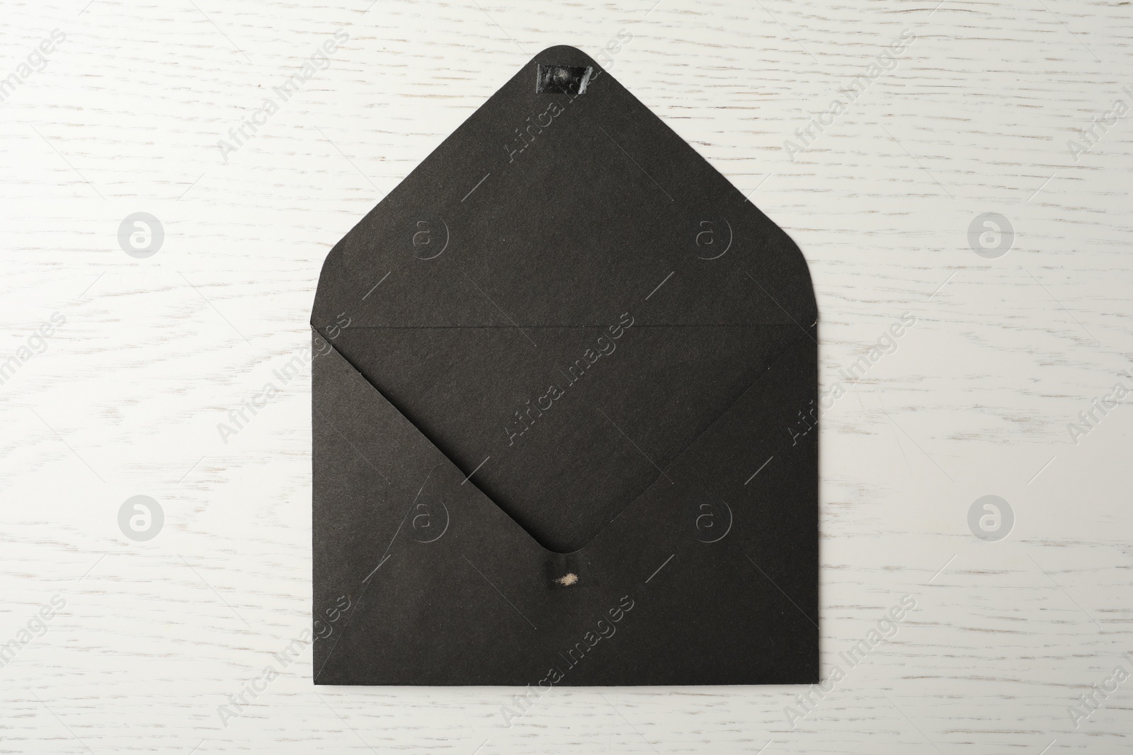 Photo of Black paper envelope on white wooden background, top view