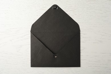 Black paper envelope on white wooden background, top view