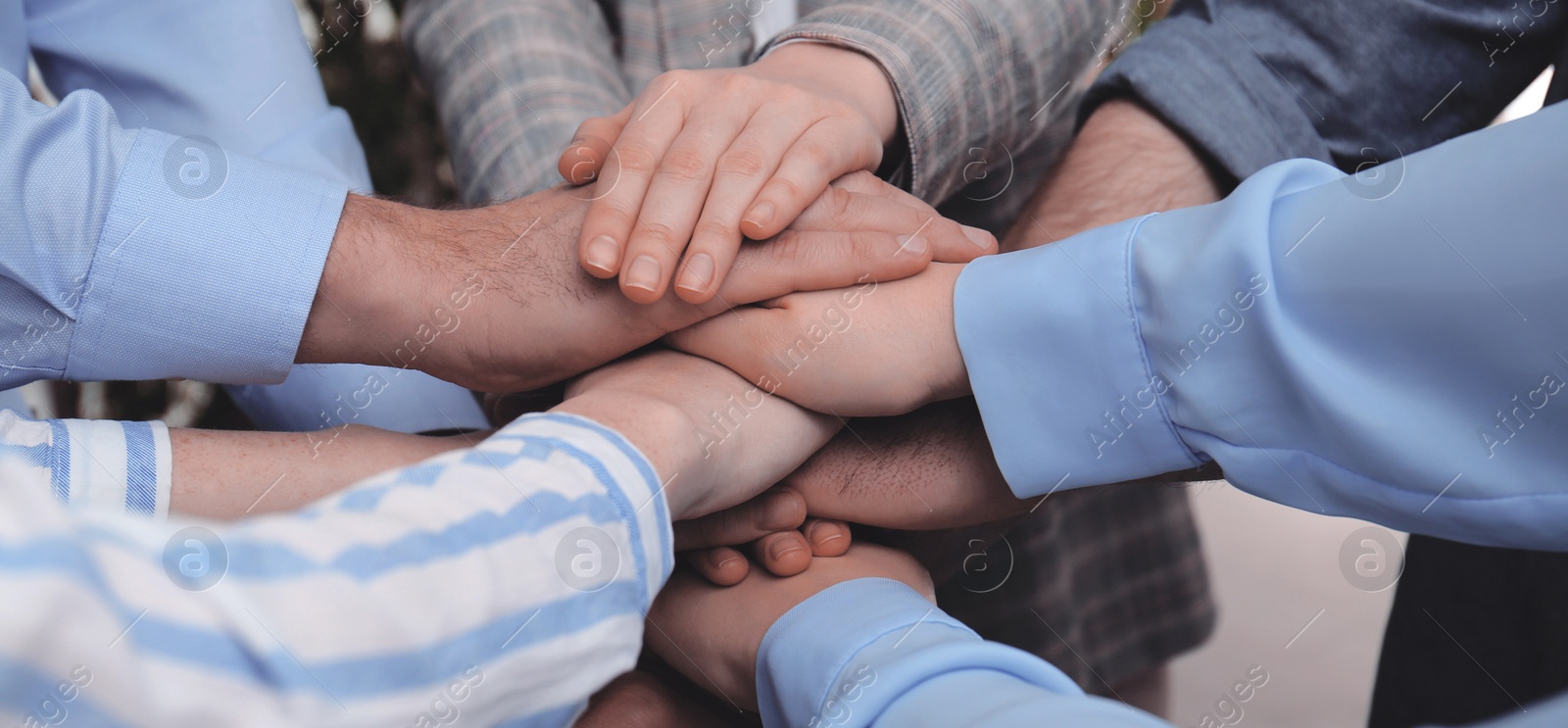 Image of Business partners. Group of people holding hands together in office, closeup. Banner design