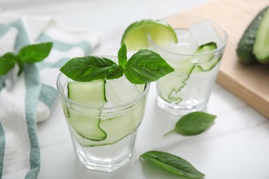 Photo of Tasty fresh cucumber water with sliced lime and basil on white marble table